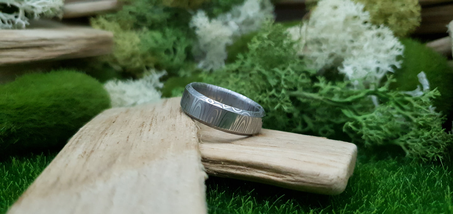 Close-up of handcrafted Damascus steel wedding band with bevel edge
