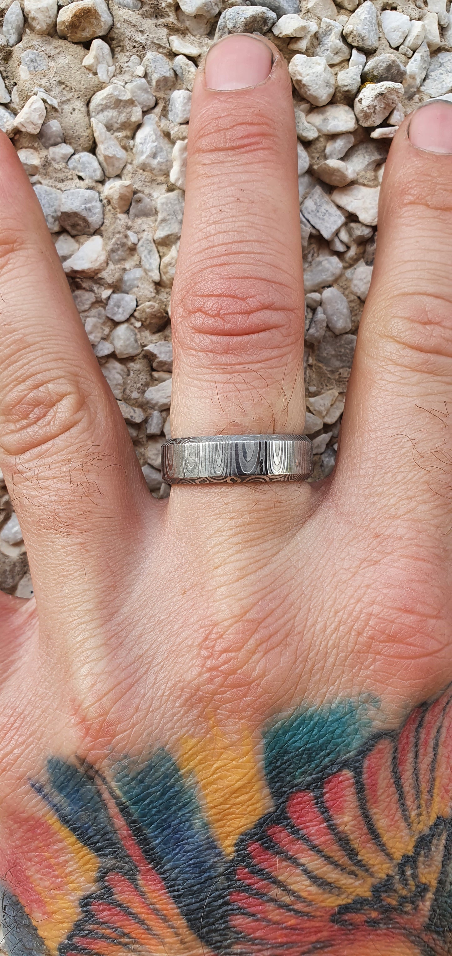 Close-up of handcrafted Damascus steel wedding band with bevel edge