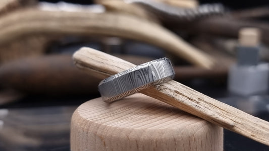 Close-up of handcrafted Damascus steel wedding band with bevel edge