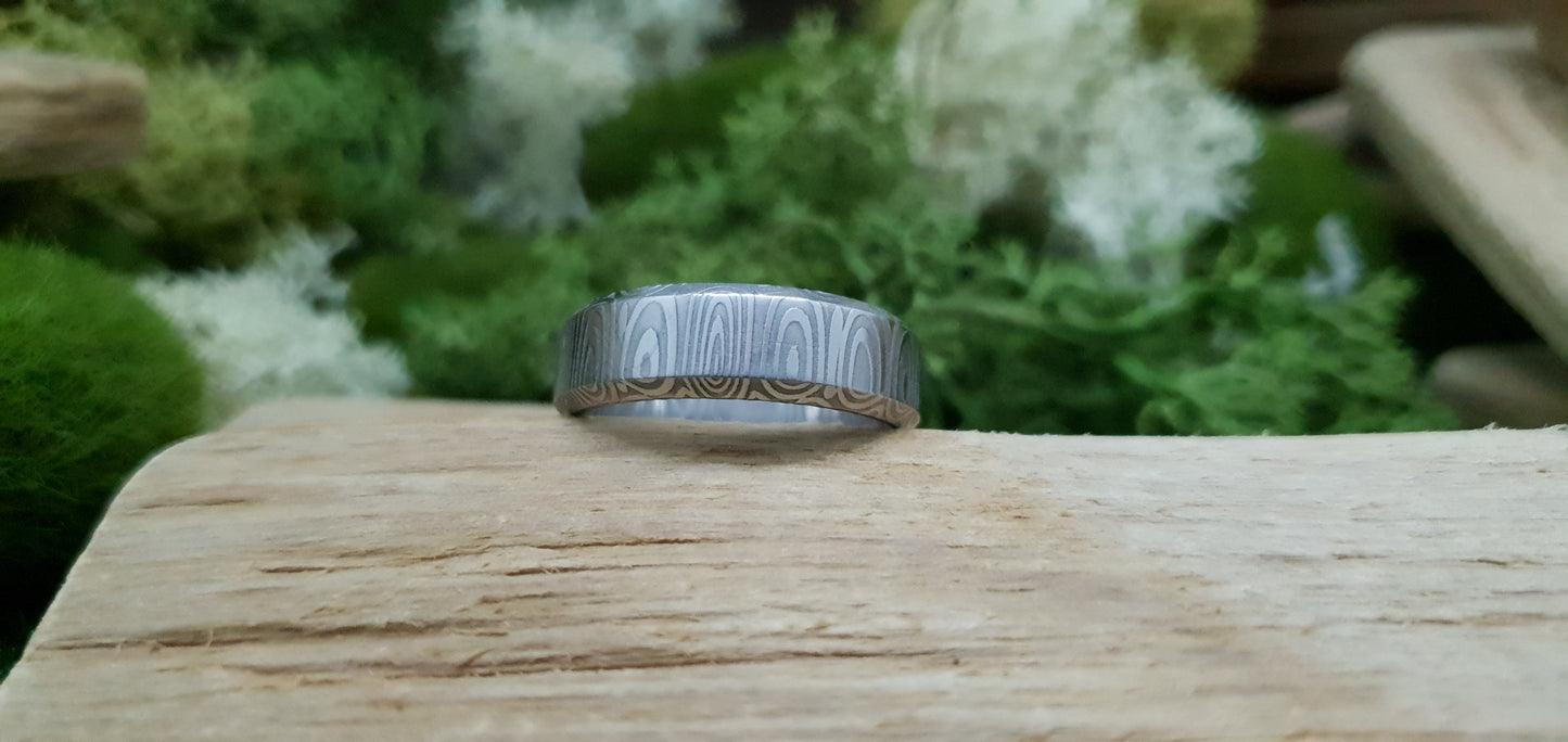Close-up of handcrafted Damascus steel wedding band with bevel edge