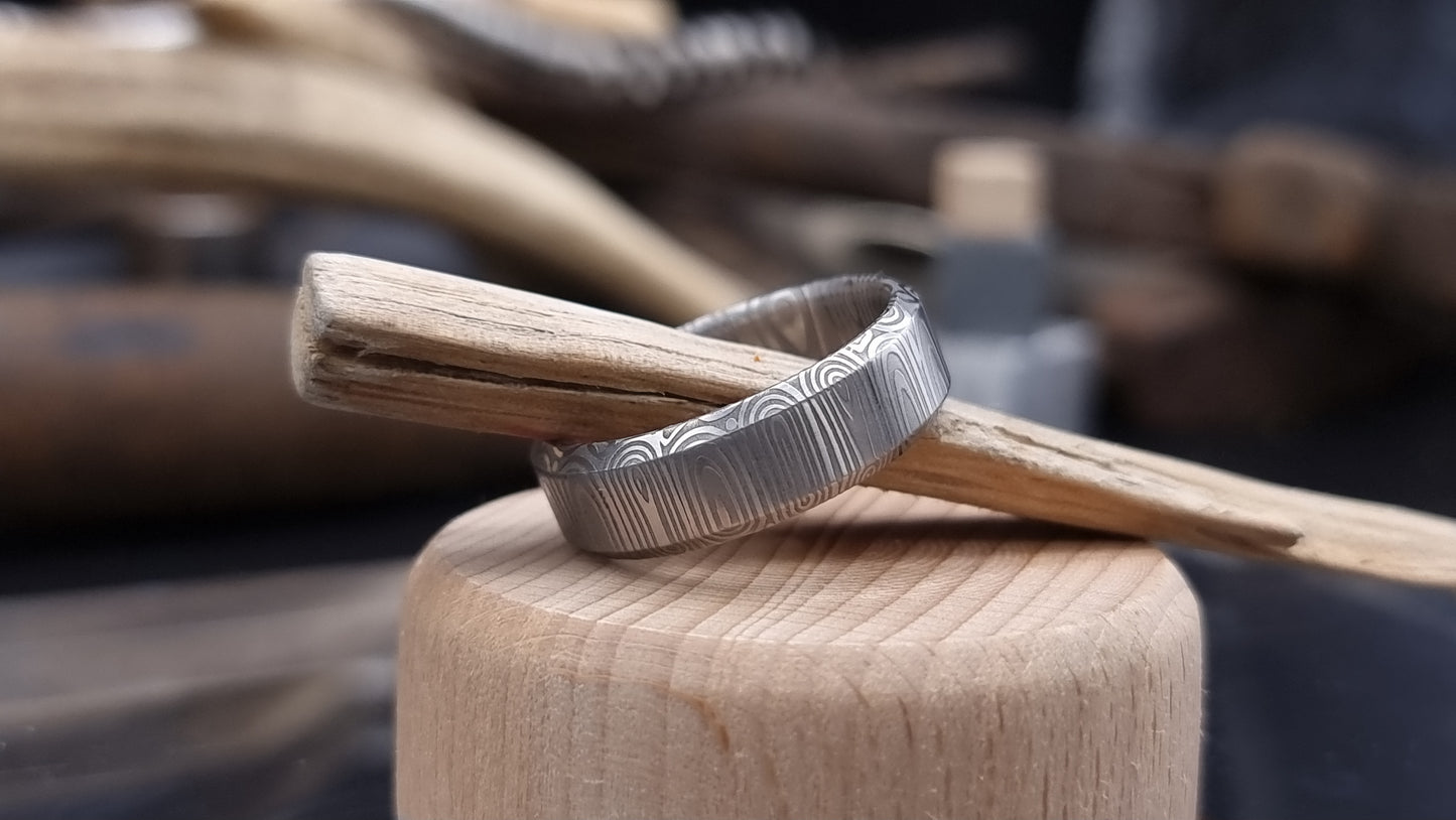 Close-up of handcrafted Damascus steel wedding band with bevel edge