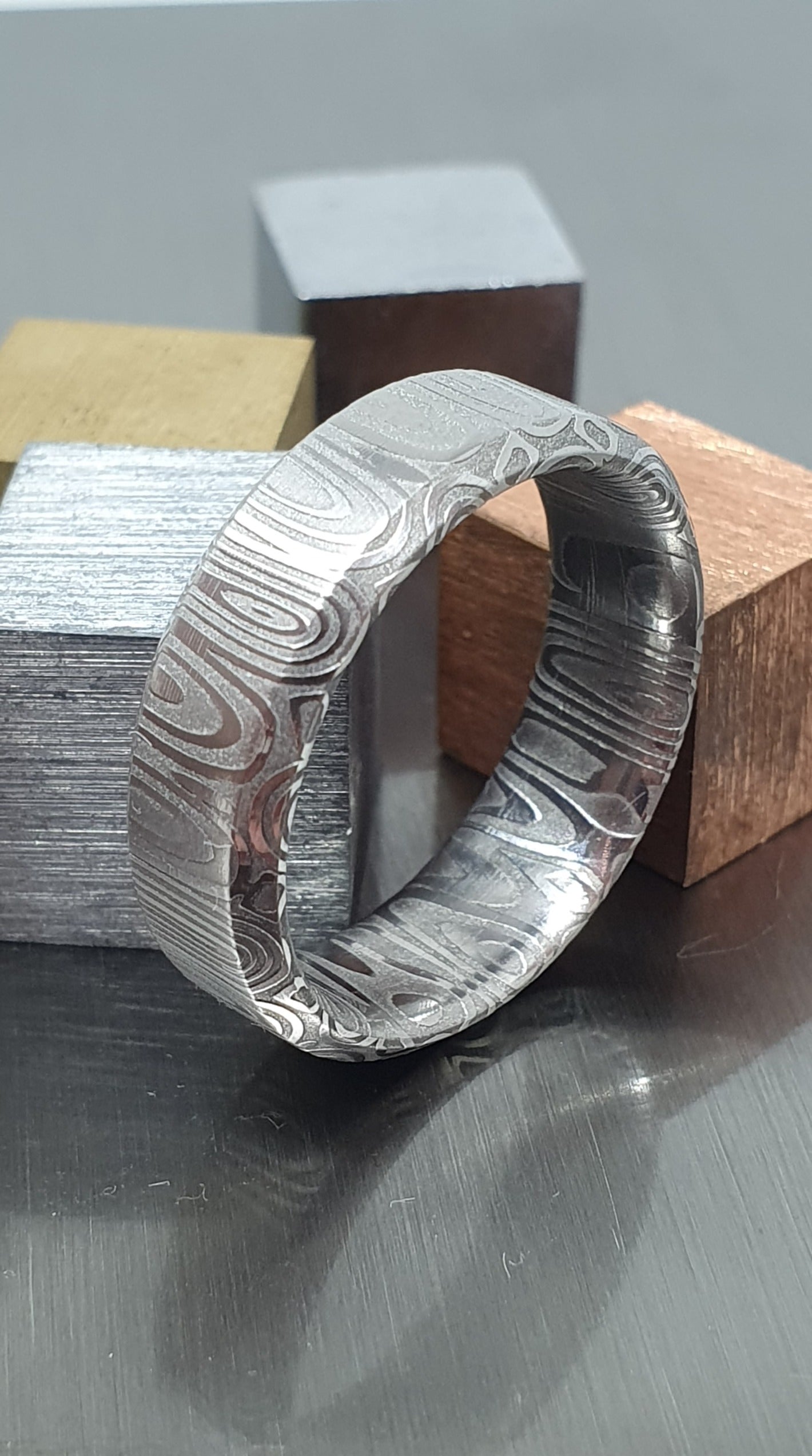 Close-up of handcrafted Damascus steel wedding band with bevel edge
