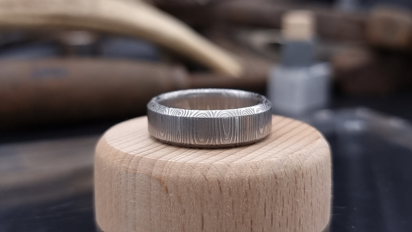 Close-up of handcrafted Damascus steel wedding band with bevel edge
