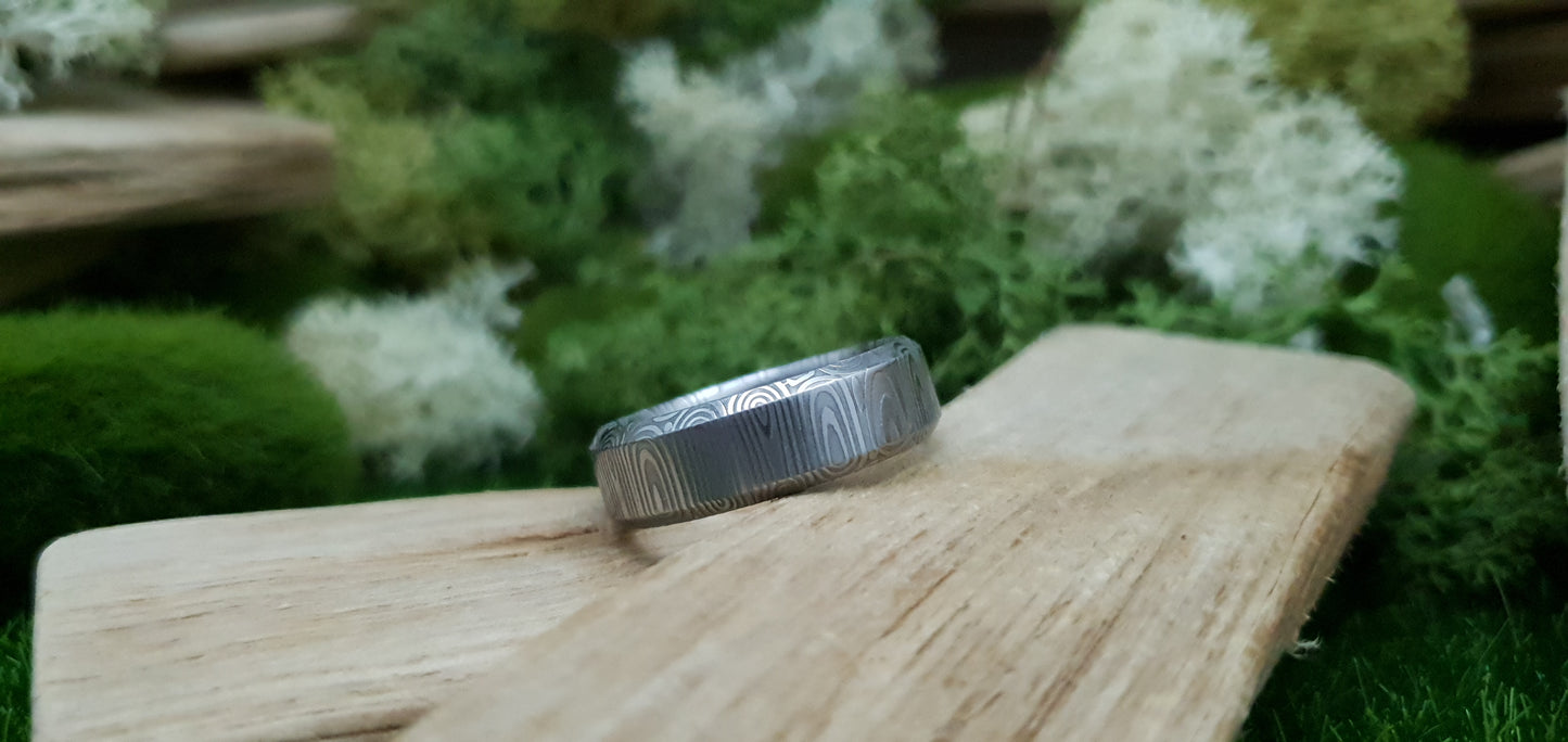 Close-up of handcrafted Damascus steel wedding band with bevel edge