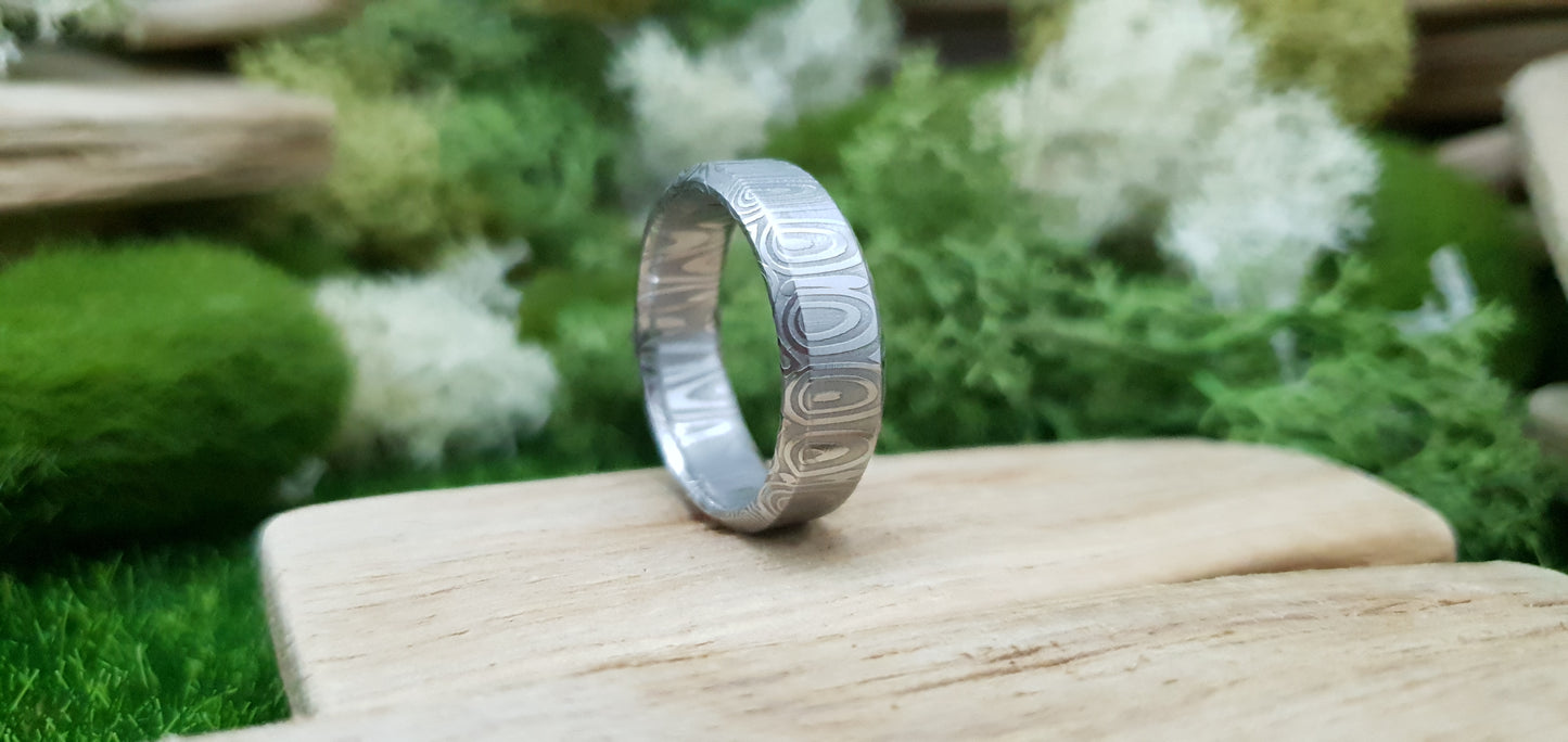 Close-up of handcrafted Damascus steel wedding band with bevel edge